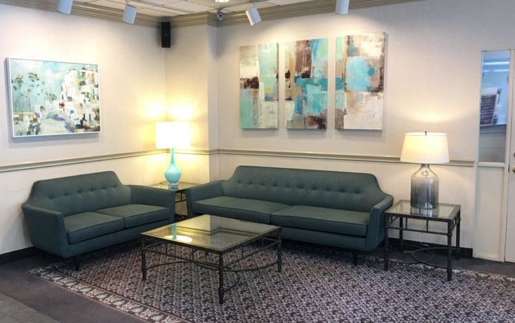 Roosevelt Inn's lobby, showing two couches and tables, with paintings on the walls